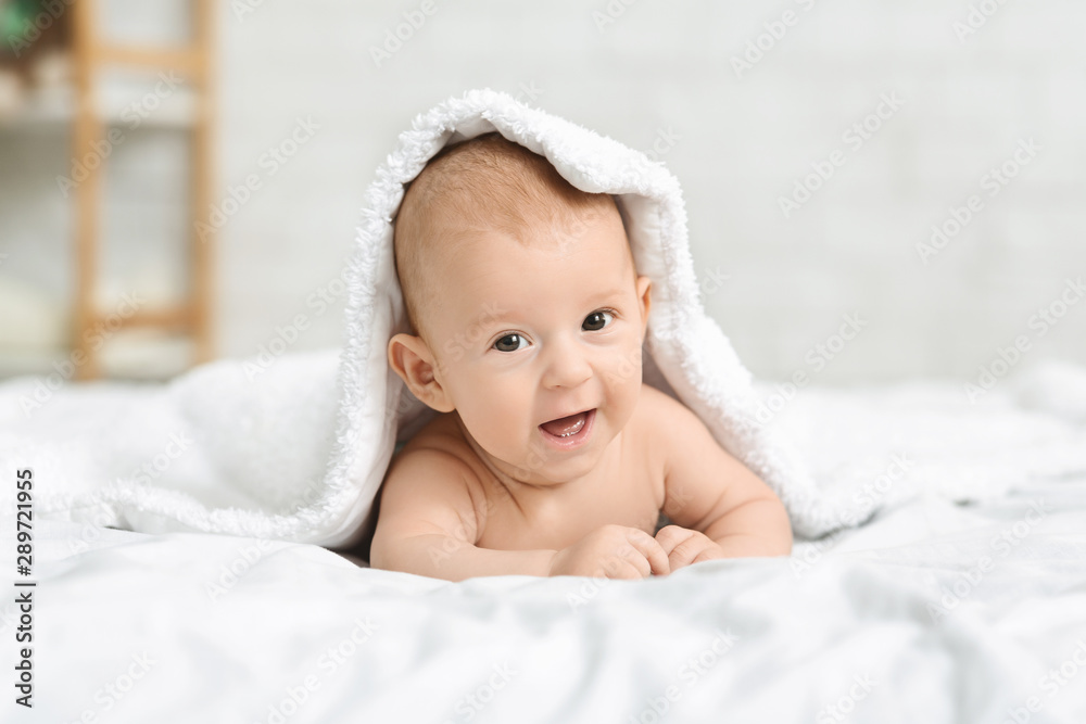 Happy little baby crawling on bed under blanket Happy little baby crawling on bed under blanket