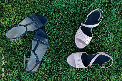 Black and pink women's sandals on the grass top view. Summer women's shoes in the park on a green lawn.