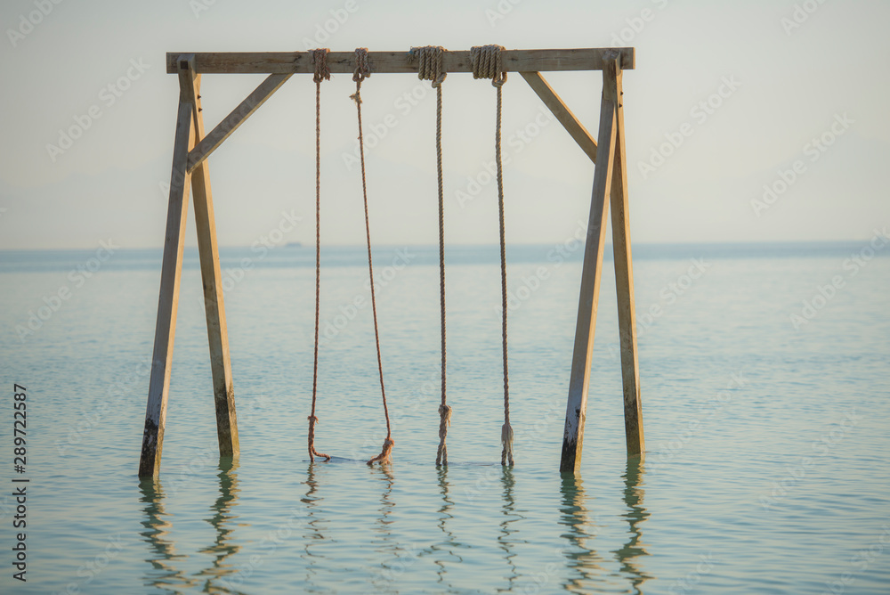 Wooden swing in shallow water on tropical beach Wooden swing in shallow water on tropical beach