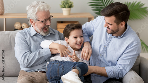 Happy three generation men family playing laughing tickling on sofa