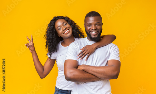 Happy young couple posing over yellow studio background