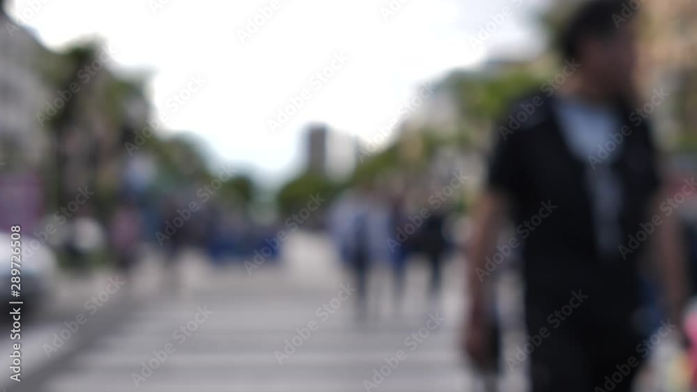 people are walking on a pedestrian crossing near a passing car on the street, out of focus people are walking on a pedestrian crossing near a passing car on the street, out of focus