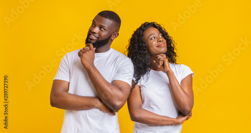 Young couple day dreaming on yellow background