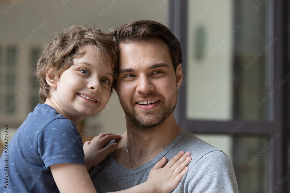 Young smiling father holding little preschool son on hands. Young smiling father holding little preschool son on hands.