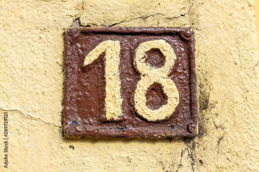 Number 18, eighteen, street number sign on the wall Number 18, eighteen, street number sign on the wall