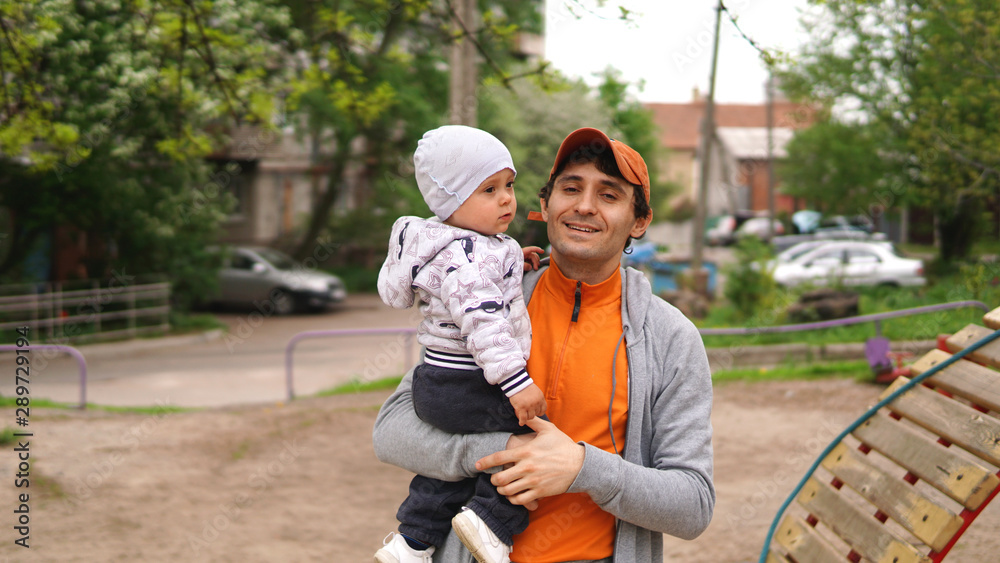 Handsome smiling adult father holding cute little baby on his arms Handsome smiling adult father holding cute little baby on his arms