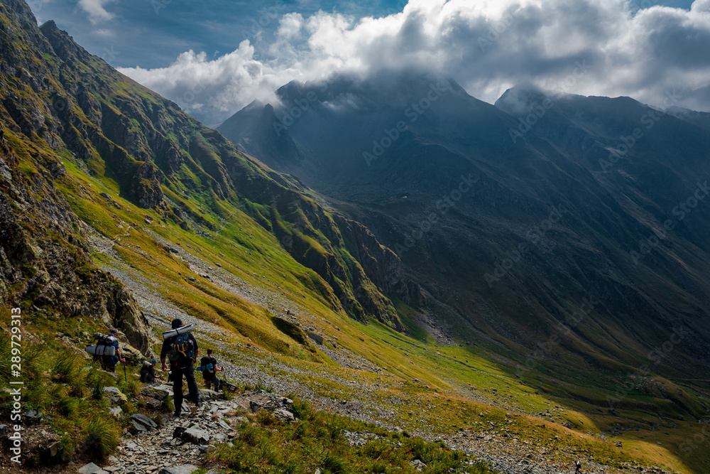 Fototapeta premium Tourists walking on the path from the top of the mountain. Fagaras Mountains, Romania