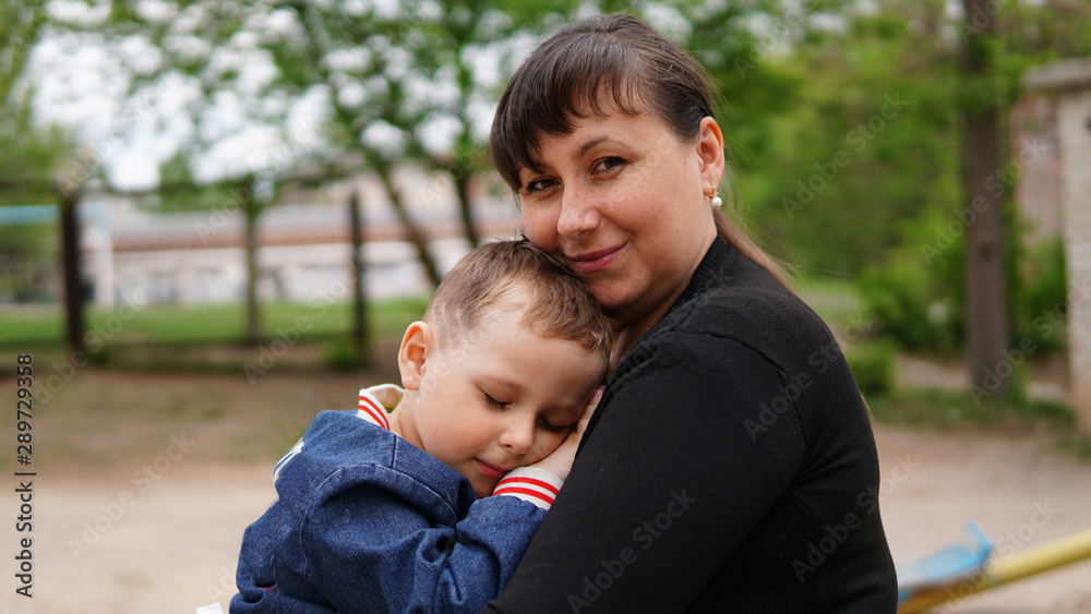 Smiling woman hug cute little boy on playground. Boy close eyes Smiling woman hug cute little boy on playground. Boy close eyes