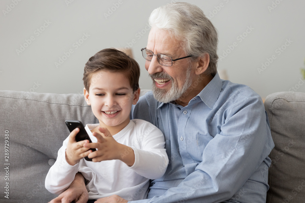 Happy senior grandfather and grandson using smart phone at home Happy senior grandfather and grandson using smart phone at home