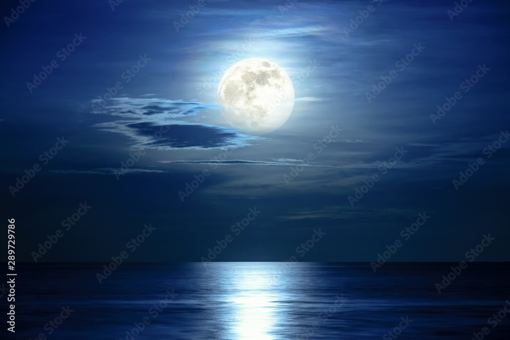 Super full moon and cloud in the blue sky above the ocean horizon at midnight, moonlight reflect the water surface and wave, Beautiful nature landscape view at night scene of the sea for background