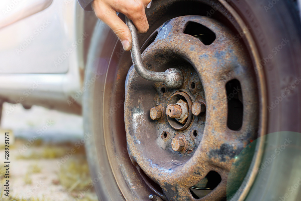 replacing a wheel in a car, loosening nuts with a hand wrench. Stock