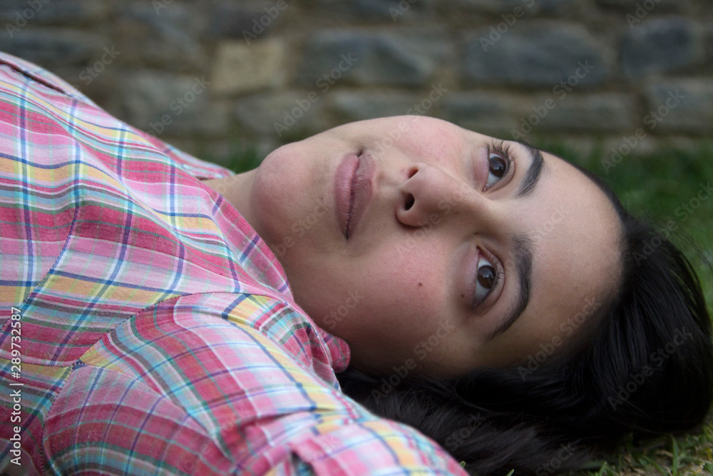 A female teenager laying on the grass thinking, wondering or nostalgia concept A female teenager laying on the grass thinking, wondering or nostalgia concept