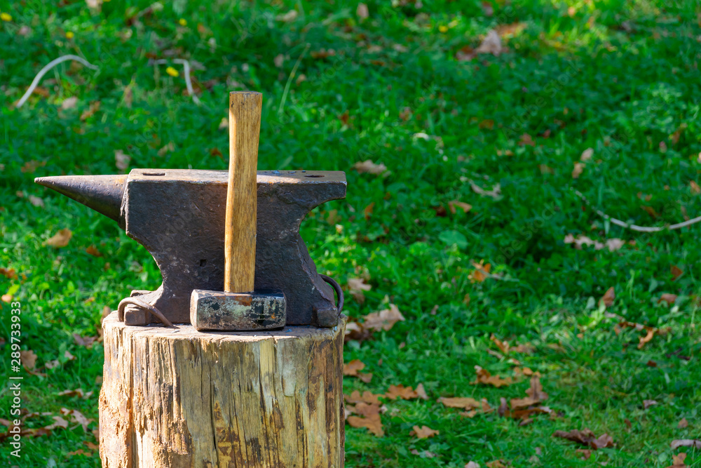 On the stump of a blacksmith's tools: hammer and anvil. The concept of manual labor, craft. Copy space On the stump of a blacksmith's tools: hammer and anvil. The concept of manual labor, craft. Copy space