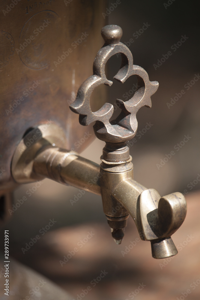 Details of an old bronze samovar wood burning outdoor, preparing water for tea brewing, selective focus Details of an old bronze samovar wood burning outdoor, preparing water for tea brewing, selective focus