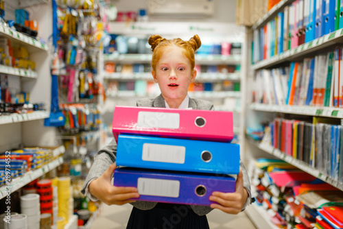 School girl holds folders in stationery store