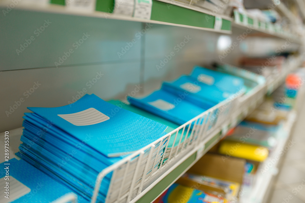 Fototapeta premium Shelf with notebooks in stationery store, nobody