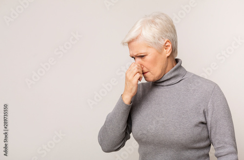 Canvas Print Senior woman closing nose because of bad smell