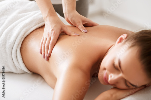 Young girl receiving back massage with closed eyes