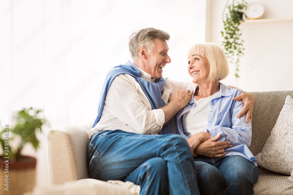 Senior affectionate couple relaxing on sofa at home