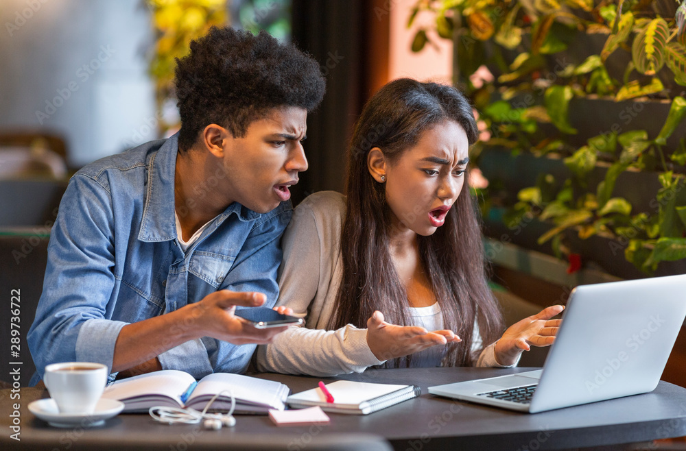 Desperate students looking at laptop with furious faces Desperate students looking at laptop with furious faces
