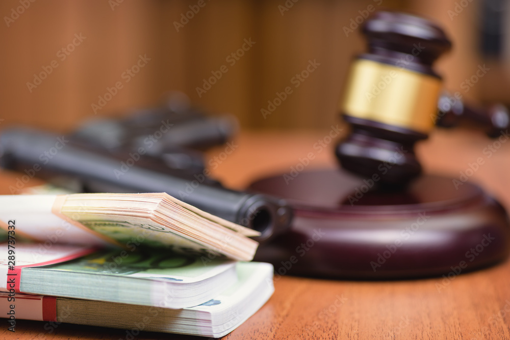 Money, gun and judge's gavel on the table. Trial for robbery with murder. Murder and robbery of businessman and the court.