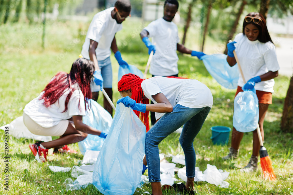 Group of happy african volunteers with garbage bags cleaning area in park. Africa volunteering, charity, people and ecology concept. Group of happy african volunteers with garbage bags cleaning area in park. Africa volunteering, charity, people and ecology concept.