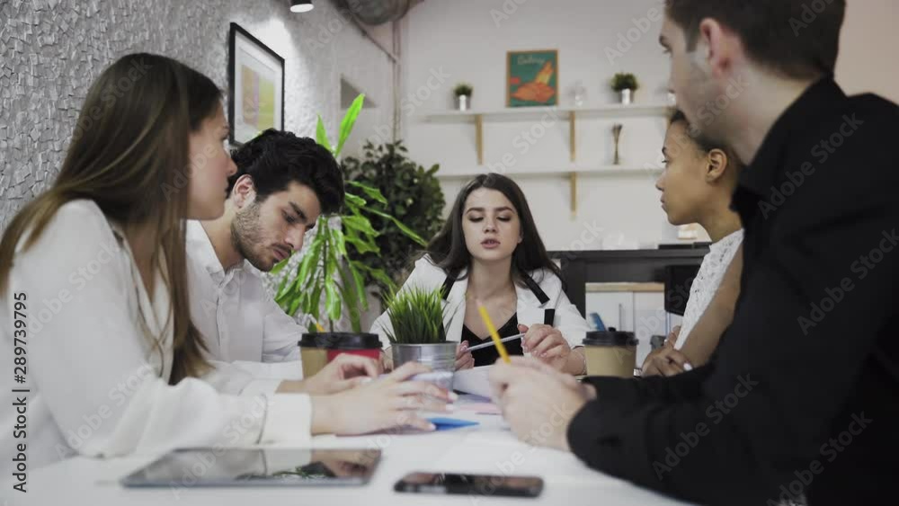 Female team leader at office meeting. Young multiethnic business people brainstorm in trendy coworking Female team leader at office meeting. Young multiethnic business people brainstorm in trendy coworking