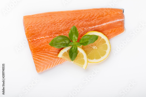 Fresh raw salmon fillets with herbs and lemon isolated on white background.