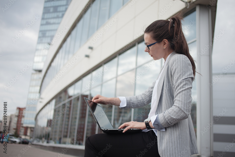 Career growth and ambitions, concept. Young businesswoman with a laptop in her hands on the background of the business center. Career growth and ambitions, concept. Young businesswoman with a laptop in her hands on the background of the business center.