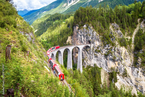 Bernina Express train on Landwasser Viaduct, Switzerland. Landscape of Alpine mountain with high bridge, Swiss landmark. Scenic view of amazing railway in summer.
