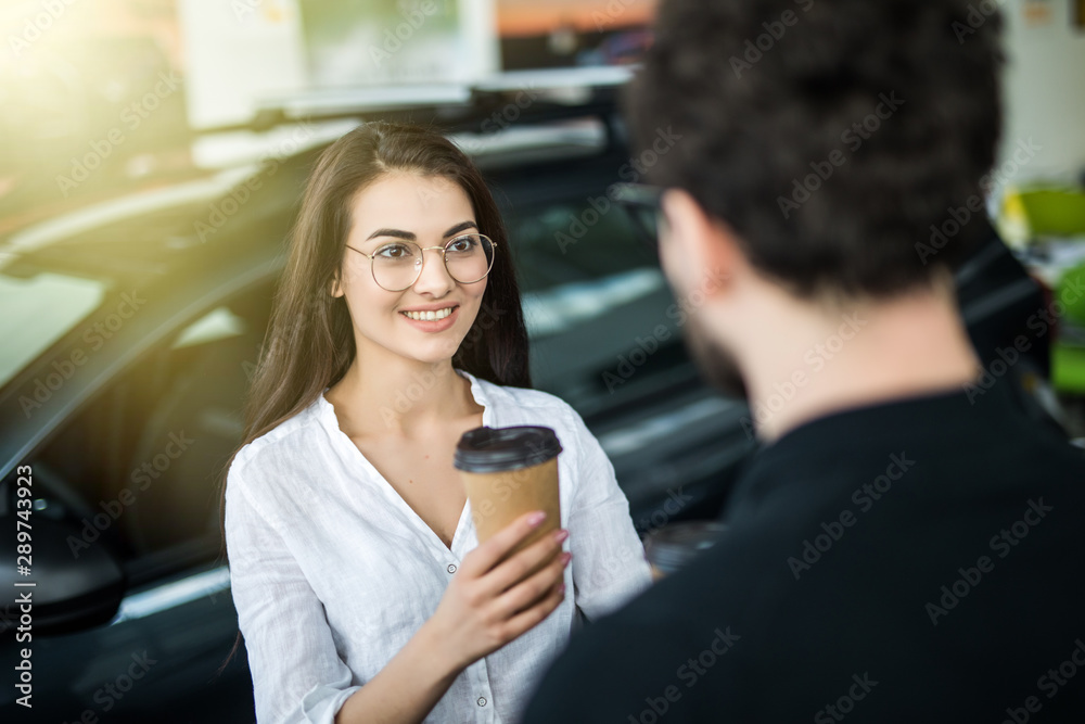 They are very happy about this, they are in a good mood. There are many modern cars. The seller helps them choose. They are very happy about this, they are in a good mood. There are many modern cars. The seller helps them choose.