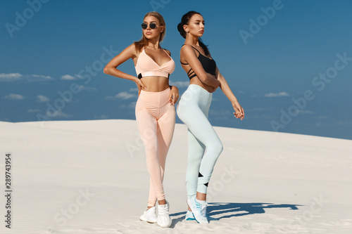 Beautiful fitness models in sportswear. Couple athletic girls in leggings outdoor photo