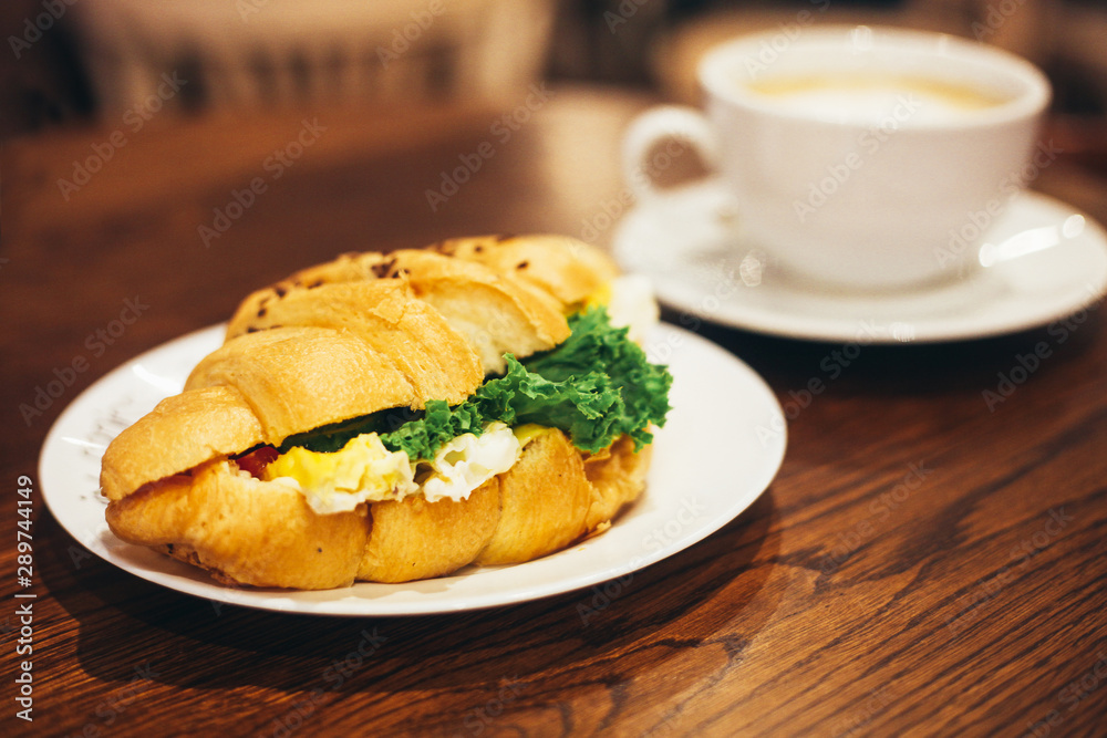 Big white cup of coffee and delicious croissant with salad on the restaurant table Big white cup of coffee and delicious croissant with salad on the restaurant table