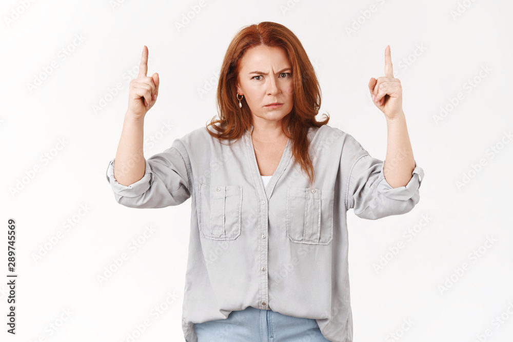 Explain yourself young man. Angry displeased middle-aged redhead mother frowning pointing up index finger dangerous annoyed stare camera scolding child bad behaviour standing white background upset Explain yourself young man. Angry displeased middle-aged redhead mother frowning pointing up index finger dangerous annoyed stare camera scolding child bad behaviour standing white background upset