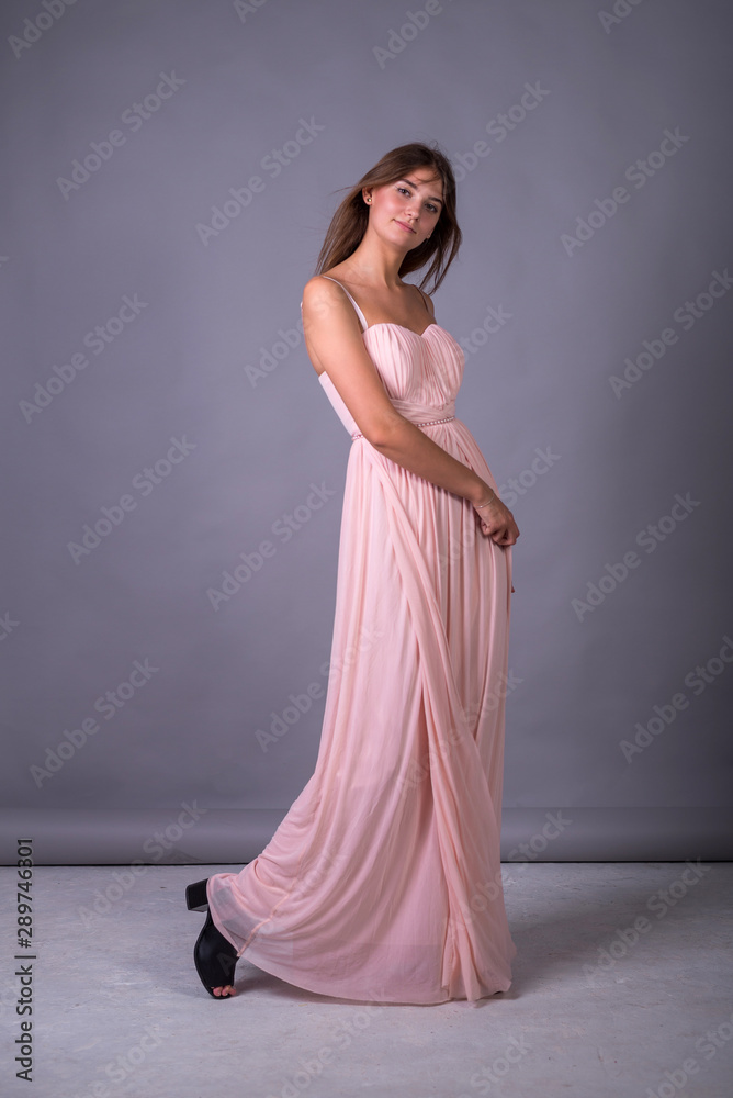 Young girl in a pink dress posing on a gray background. Young girl in a pink dress posing on a gray background.