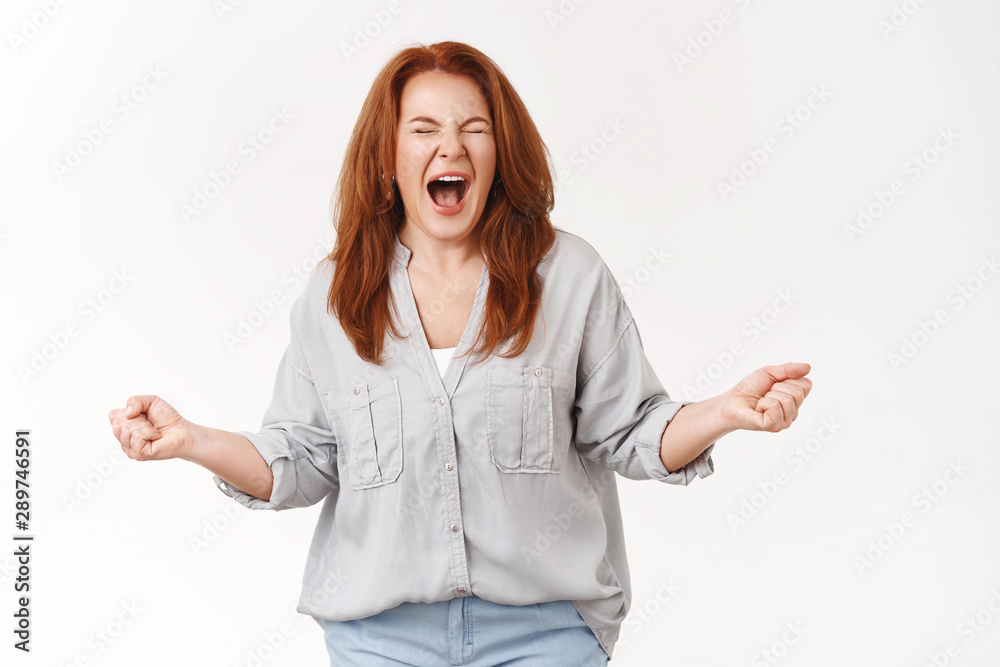 Woman cannot stand pressure release stress shouting fed up. Distressed annoyed redhead middle-aged mother clench fists close eyes yelling break free negative emotions, standing white background Woman cannot stand pressure release stress shouting fed up. Distressed annoyed redhead middle-aged mother clench fists close eyes yelling break free negative emotions, standing white background