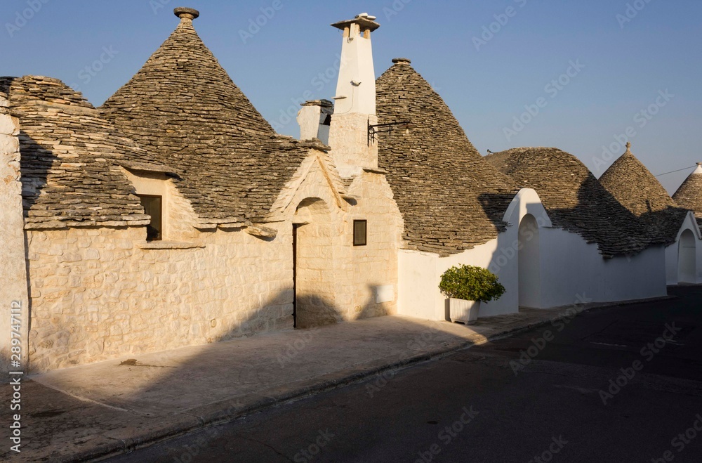 ALBEROBELLO, ITALY - AUGUST 27 2017: View at sunset light of traditional row of trullo houses