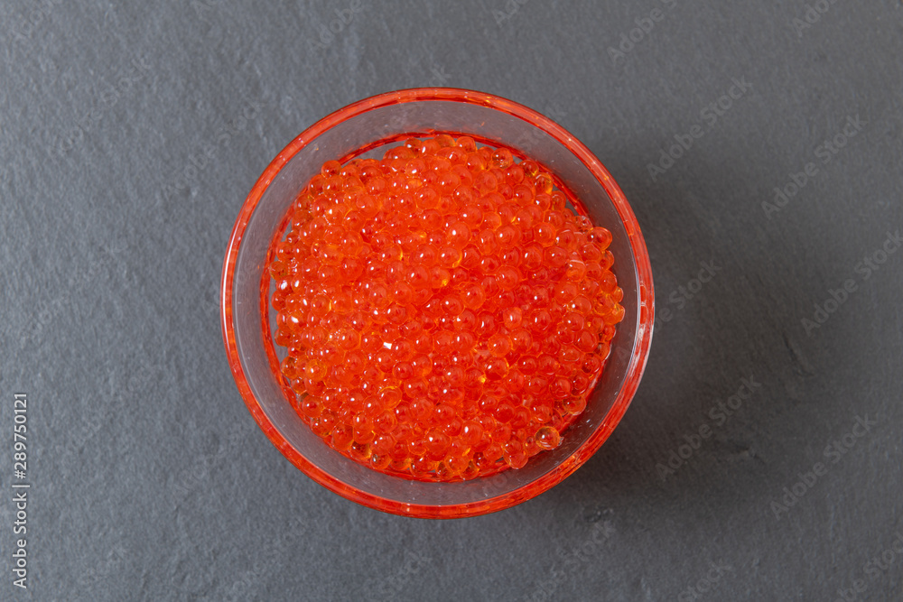 Red caviar in the glass jar on the grey stone background Red caviar in the glass jar on the grey stone background