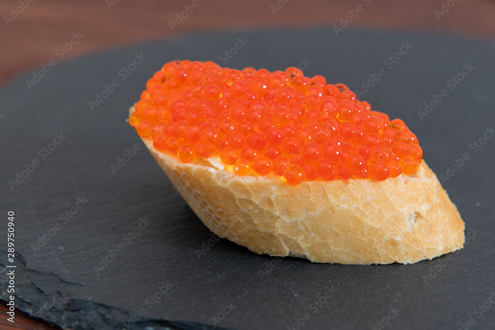 Red caviar with white bread on the grey stone background Red caviar with white bread on the grey stone background