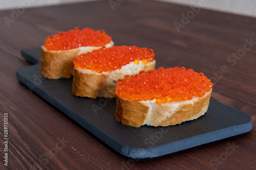Set of three sandwiches with red caviar on the grey stone background