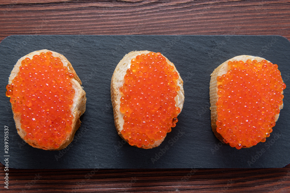 Set of three sandwiches with red caviar on the grey stone background Set of three sandwiches with red caviar on the grey stone background