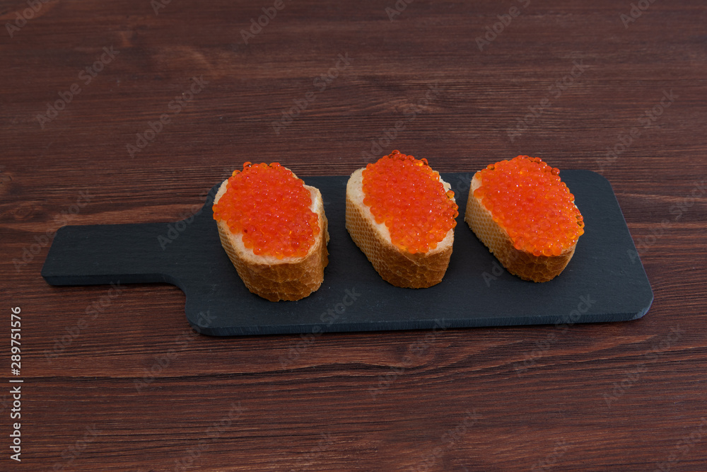 Set of three sandwiches with red caviar on the grey stone background Set of three sandwiches with red caviar on the grey stone background