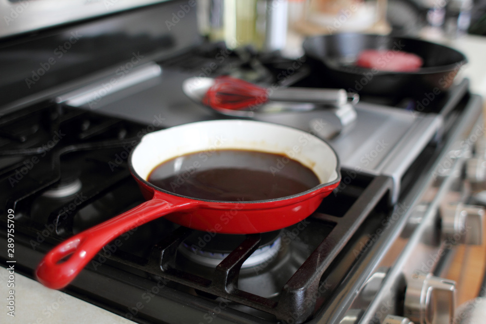 Demi-glace cooked in a coated enamel skillet on the stove top in a home kitchen. Demi-glace cooked in a coated enamel skillet on the stove top in a home kitchen.