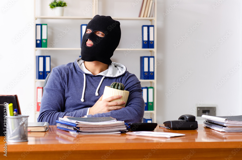 Male thief in balaclava in the office Male thief in balaclava in the office