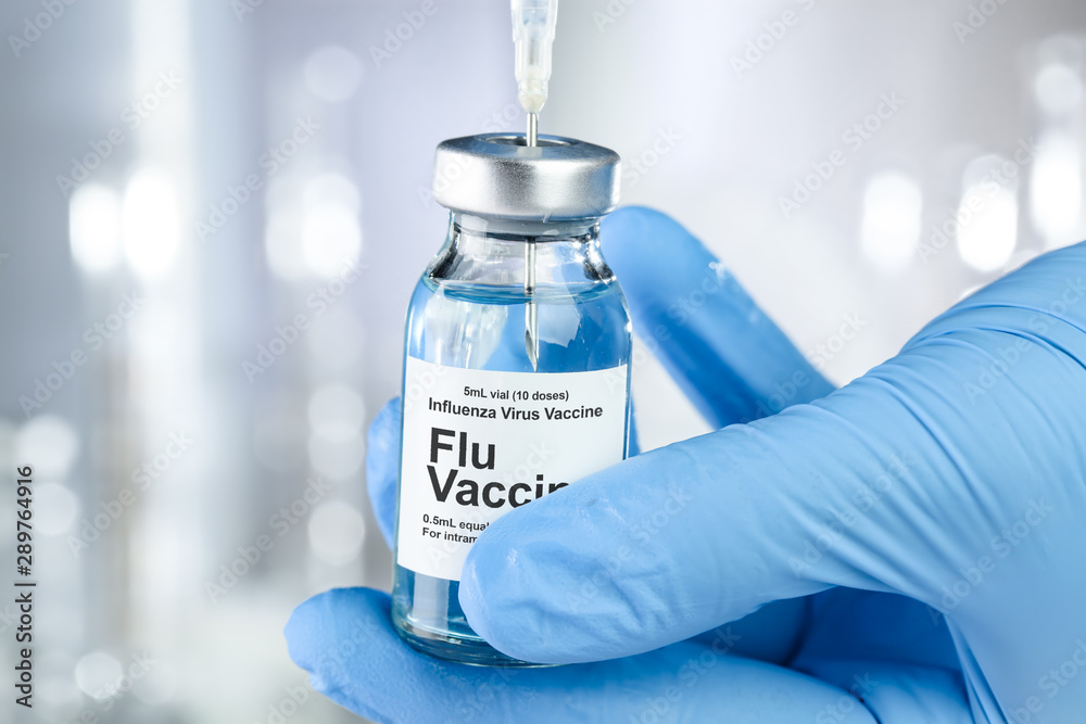 Healthcare concept with a hand in blue medical gloves holding Flu, Influenza, vaccine vial Healthcare concept with a hand in blue medical gloves holding Flu, Influenza, vaccine vial