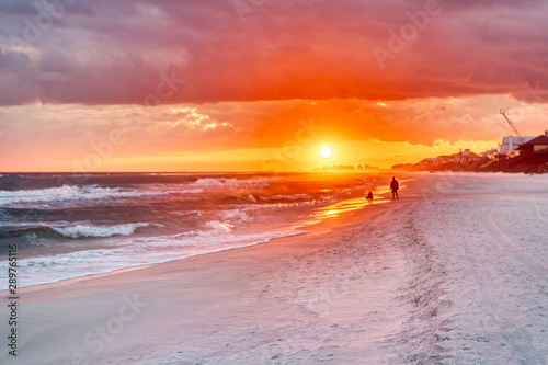 Couple looking at colorful sunset in Santa Rosa Beach with Pensacola coast in Florida Panhandle at Gulf of Mexico ocean waves