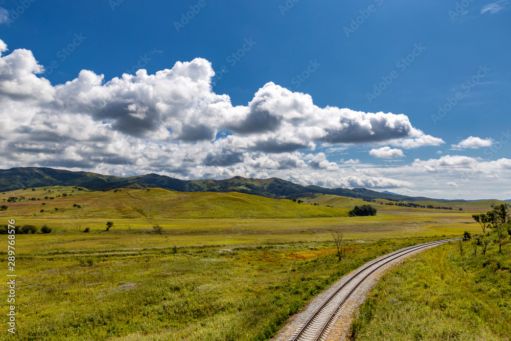 Railroad and countryside scenery with green hills and blue sky