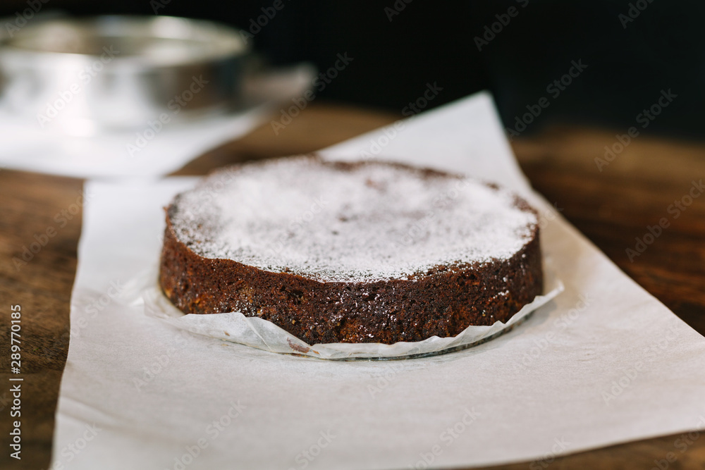 Traditional lumberjack fruit cake dusted with powdered sugar on parchment baking paper on wood surface with sheet pan in background Traditional lumberjack fruit cake dusted with powdered sugar on parchment baking paper on wood surface with sheet pan in background