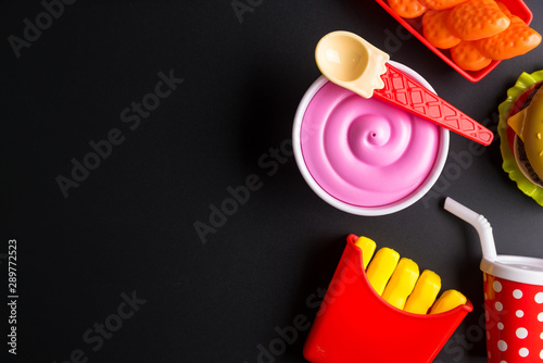 Plastic burger, French fries Fast food on black background. Children's toy. Concept of harmful artificial food. Plastic. Not organic. Not useful. © bubbers