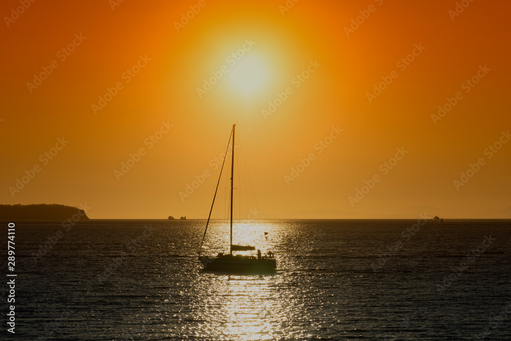 Silhouette of the yacht against the bright orange sunset.